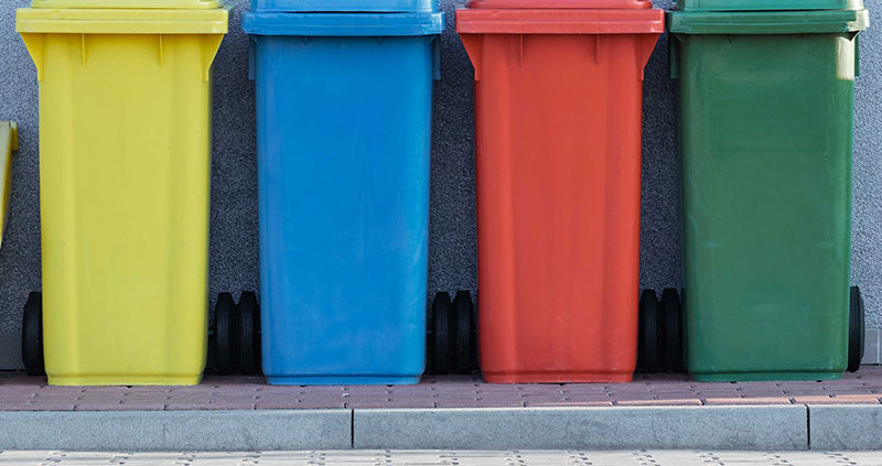 Four colorful recycling bins on a curb